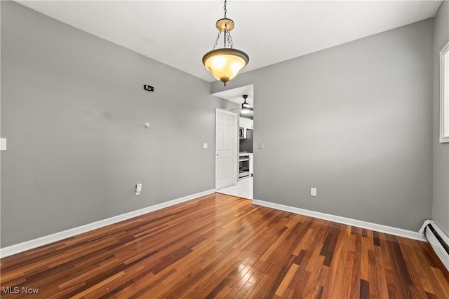 unfurnished room with ceiling fan, wood-type flooring, and a baseboard heating unit