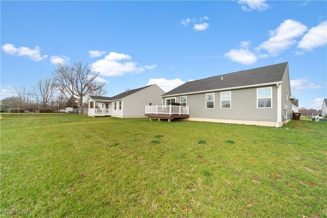 rear view of property featuring a lawn and a deck