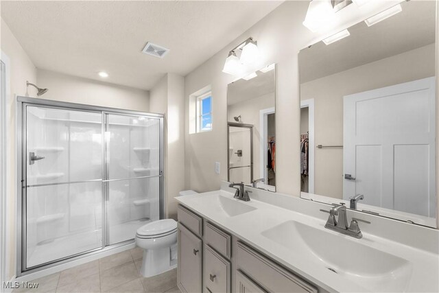 bathroom featuring tile patterned floors, toilet, vanity, and walk in shower