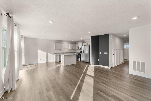 unfurnished living room with a healthy amount of sunlight, light hardwood / wood-style floors, and a textured ceiling