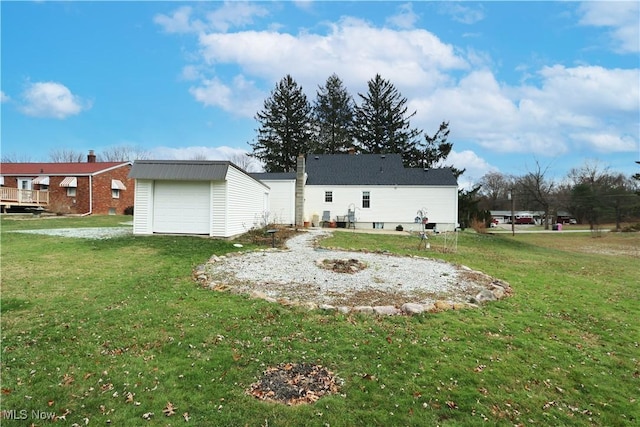 back of house featuring a yard, a garage, and an outdoor structure