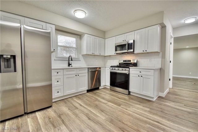 kitchen with light hardwood / wood-style floors, sink, white cabinetry, and stainless steel appliances