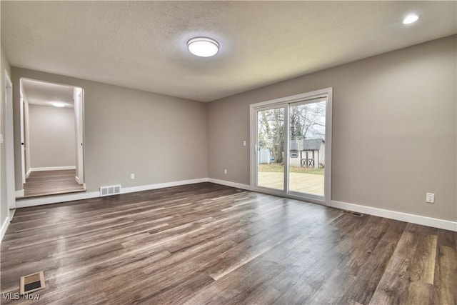 empty room featuring a textured ceiling and dark wood-type flooring