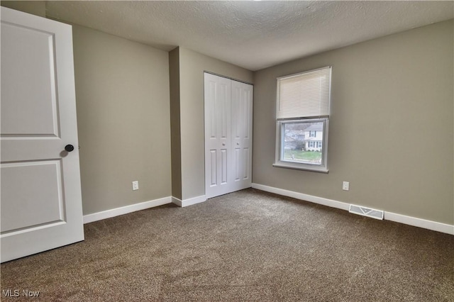 unfurnished bedroom with a closet, carpet floors, and a textured ceiling