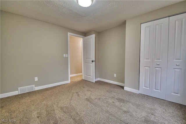 unfurnished bedroom with carpet, a textured ceiling, and a closet