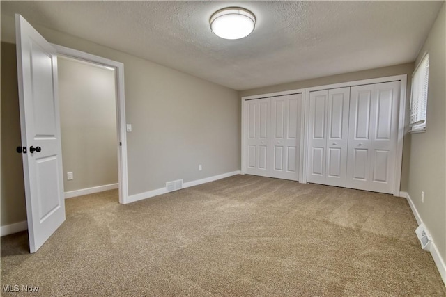 unfurnished bedroom with multiple closets, carpet floors, and a textured ceiling