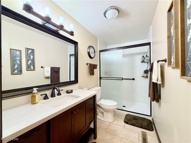 bathroom with toilet, vanity, and a shower with shower door