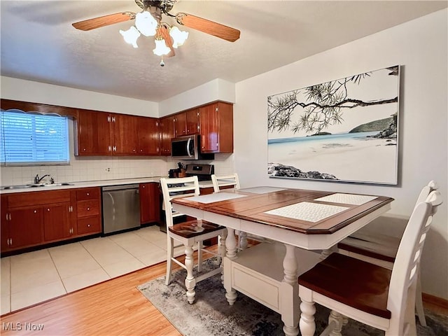 kitchen featuring sink, stainless steel appliances, a textured ceiling, decorative backsplash, and light wood-type flooring