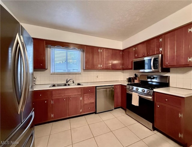 kitchen with sink, appliances with stainless steel finishes, tasteful backsplash, a textured ceiling, and light tile patterned flooring