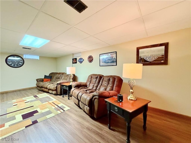 living room with hardwood / wood-style flooring and a paneled ceiling