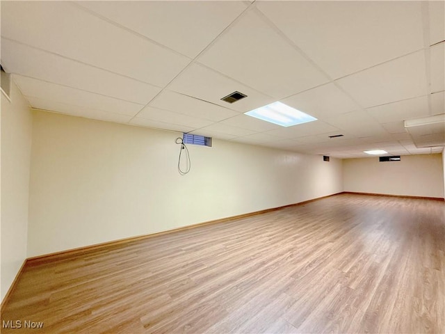 basement with hardwood / wood-style flooring and a paneled ceiling