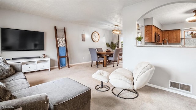 carpeted living room featuring sink and a textured ceiling