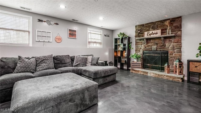 living room with a fireplace, a textured ceiling, and concrete floors