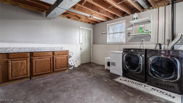 clothes washing area with washer and clothes dryer and cabinets