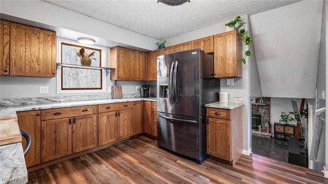 kitchen with light stone counters, stainless steel fridge, dark hardwood / wood-style flooring, and a textured ceiling