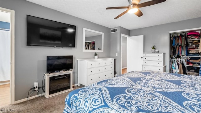 carpeted bedroom featuring a textured ceiling, a closet, and ceiling fan