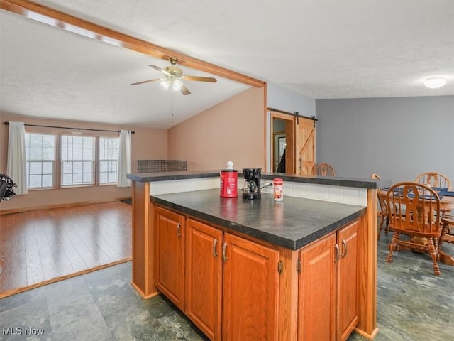 kitchen featuring ceiling fan, a center island, a barn door, a textured ceiling, and hardwood / wood-style flooring