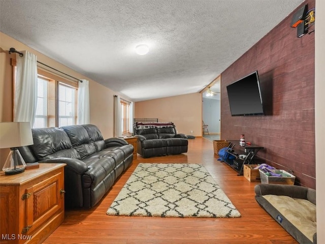 living room featuring hardwood / wood-style floors, a textured ceiling, and lofted ceiling