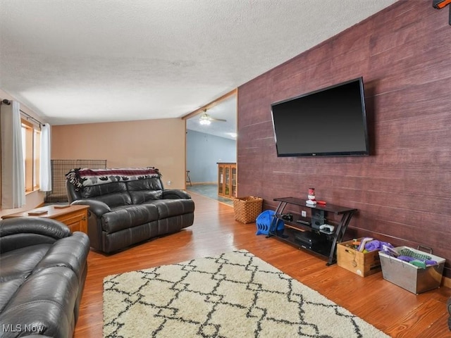 living room with hardwood / wood-style floors, ceiling fan, a textured ceiling, and vaulted ceiling