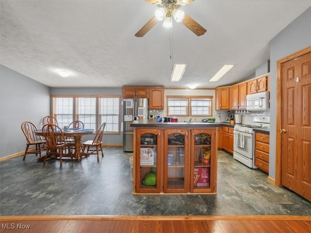 kitchen featuring a textured ceiling, dark wood-type flooring, a healthy amount of sunlight, and white appliances