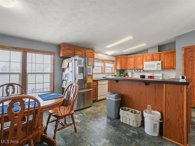 kitchen with white appliances, backsplash, vaulted ceiling, kitchen peninsula, and a breakfast bar area