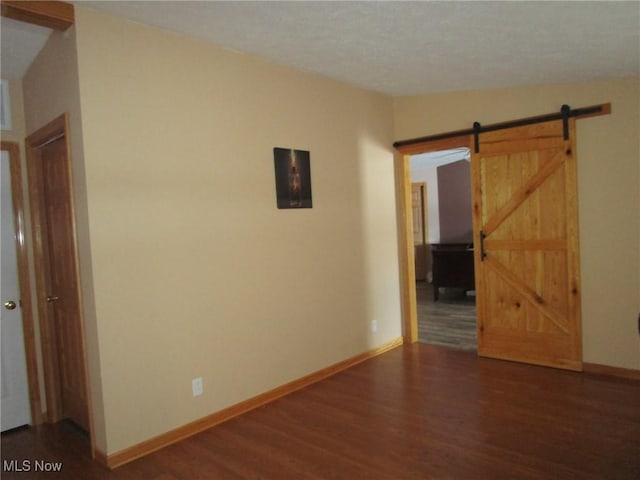 unfurnished room featuring a barn door, dark hardwood / wood-style flooring, and lofted ceiling