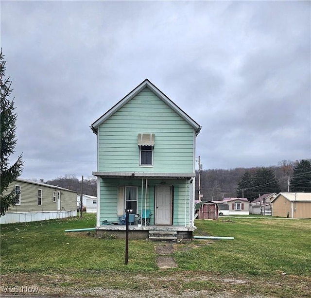 back of house with covered porch and a lawn