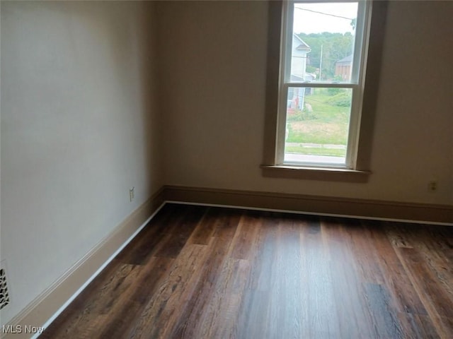 spare room featuring a healthy amount of sunlight and dark hardwood / wood-style floors