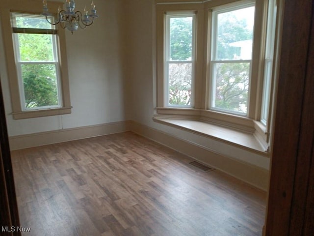 empty room featuring a chandelier and wood-type flooring