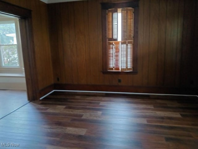 unfurnished room with wood walls and dark hardwood / wood-style flooring