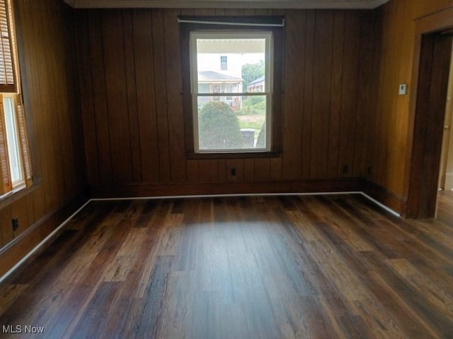 spare room featuring dark wood-type flooring and wood walls