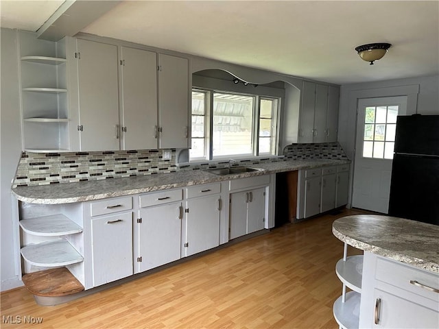 kitchen with tasteful backsplash, black fridge, plenty of natural light, and light hardwood / wood-style floors