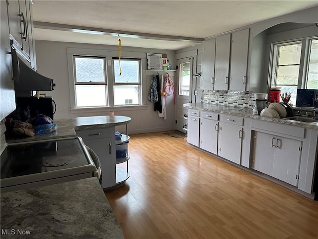 kitchen with sink, hanging light fixtures, light hardwood / wood-style flooring, decorative backsplash, and range with electric stovetop