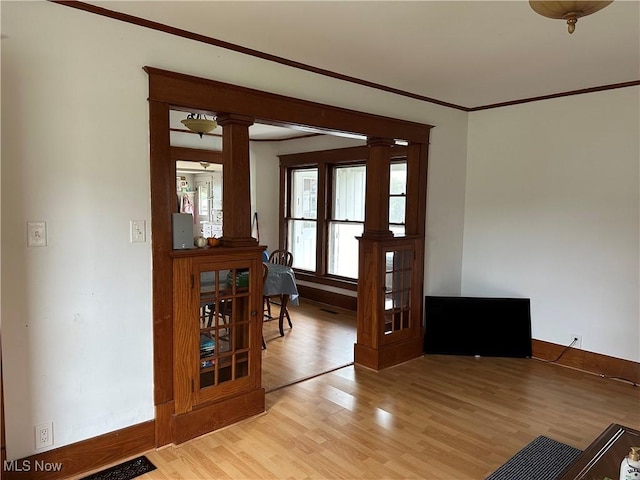 doorway to outside featuring light hardwood / wood-style floors, ornate columns, and crown molding