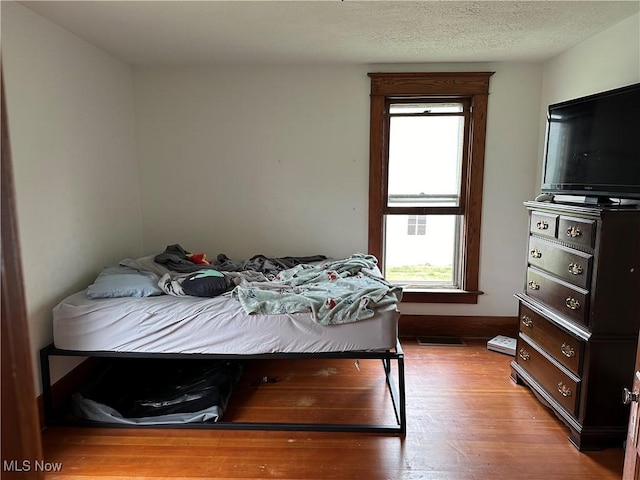 bedroom with light hardwood / wood-style floors and a textured ceiling