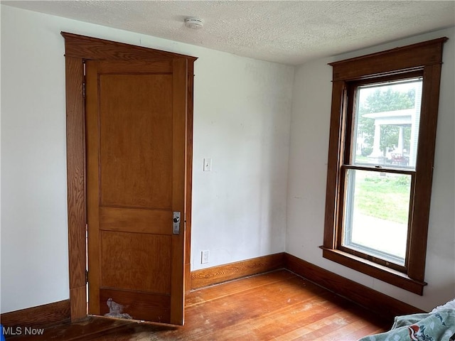 empty room with hardwood / wood-style flooring, a healthy amount of sunlight, and a textured ceiling