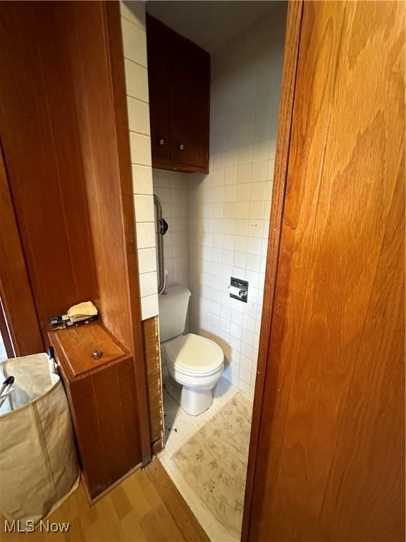 bathroom featuring tile patterned flooring, toilet, and tile walls