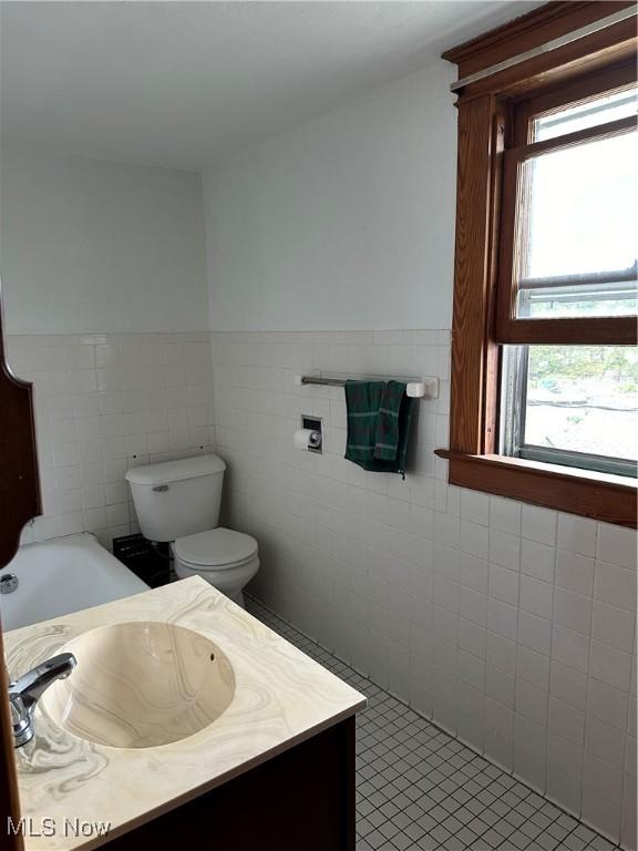 bathroom with tile patterned floors, vanity, toilet, and tile walls