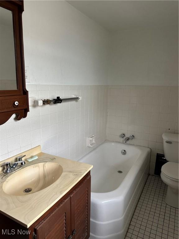 bathroom featuring tile patterned flooring, a bathtub, toilet, and tile walls