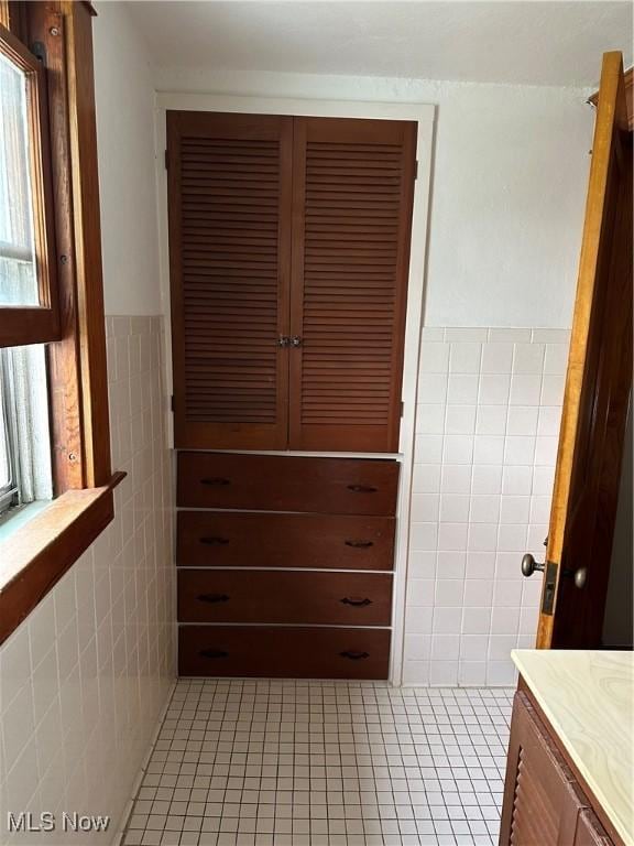 bathroom featuring tile patterned flooring, vanity, and tile walls