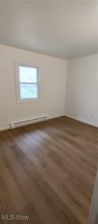 empty room featuring dark hardwood / wood-style floors and a baseboard heating unit