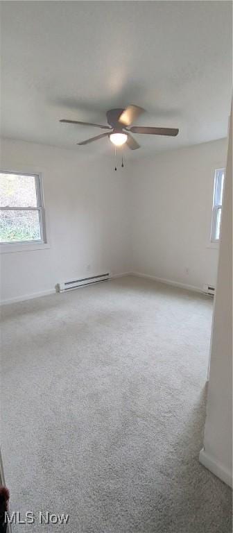 carpeted empty room featuring ceiling fan and a baseboard heating unit