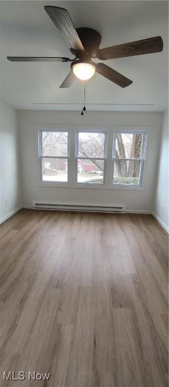 unfurnished room featuring baseboard heating and light hardwood / wood-style floors