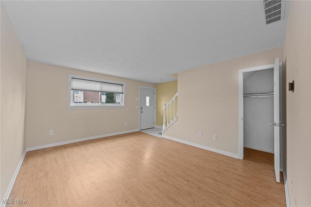 interior space with a walk in closet, a closet, and light hardwood / wood-style floors