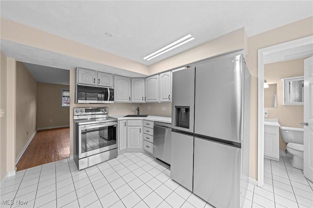 kitchen with gray cabinets, sink, light tile patterned floors, and stainless steel appliances