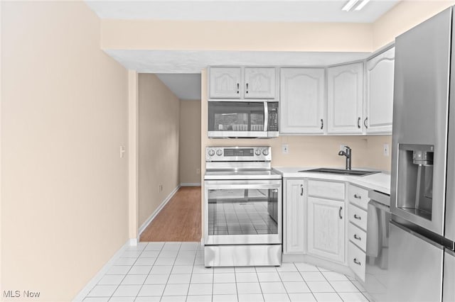 kitchen with white cabinetry, sink, light tile patterned flooring, and appliances with stainless steel finishes