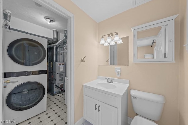 bathroom with vanity, stacked washer / drying machine, and toilet