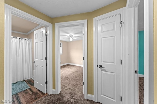 hallway with dark carpet and ornamental molding