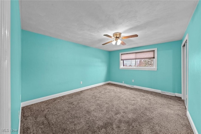 carpeted empty room featuring ceiling fan and a textured ceiling