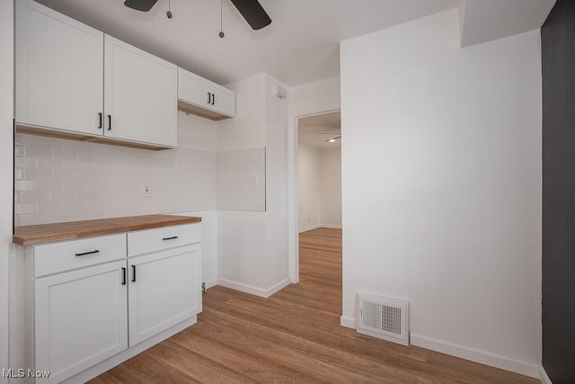 kitchen with wooden counters, backsplash, light hardwood / wood-style flooring, and white cabinetry